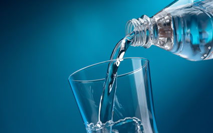 Pouring water into a glass on a blue background