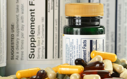 Bottle of supplements with label in background and pills in the foreground
