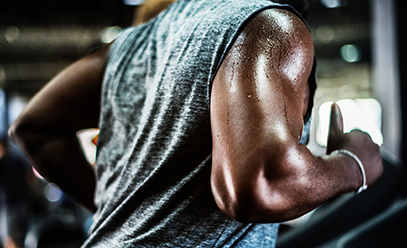 Black man running on a treadmill, sweat running down his shoulder