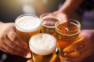 Four beer glasses at an angle from above, clinking in a cheers movement
