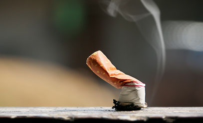 Still smoking cigarette that has been put out on a stone or rock table