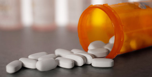 Three white prescription capsules on a light grey background