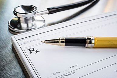 Doctors Prescription Pad with a yellow pen sitting on it. A stethoscope sits nearby
