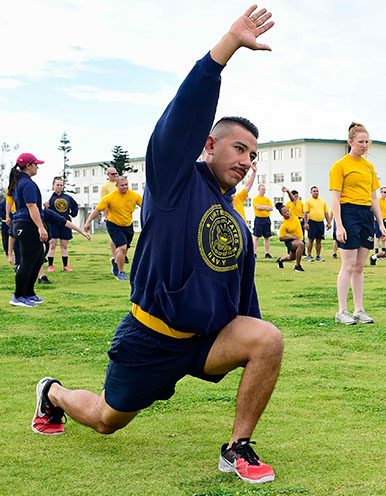 Men on a grassy field moving in warmup patterns