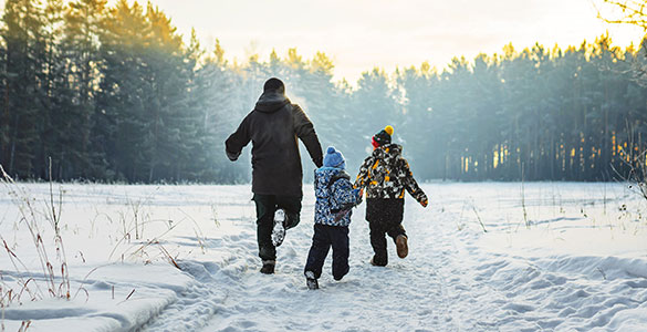 Father and two sons running playfully in the snow