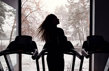 Woman on a treadmill looking out over a snowy landscape