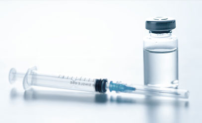 Vial of vaccine with a syringe resting next to it