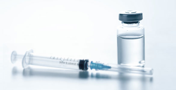 Vaccine vial with a syringe resting next to it