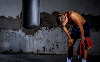 Young man resting after an intense workout on a heavy boxing bag