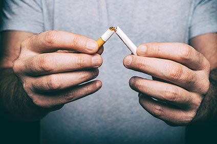 Man holding two broken halves of a cigarette