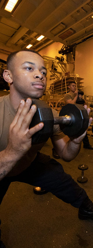 Man doing a side lunge with a dumbbell held near his chest