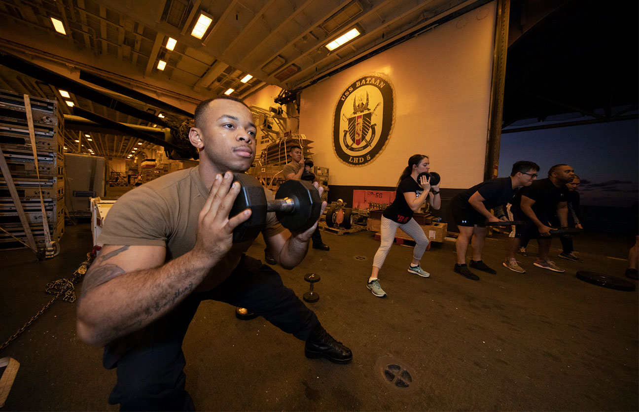 Man doing a side lunge with a dumbbell held near his chest