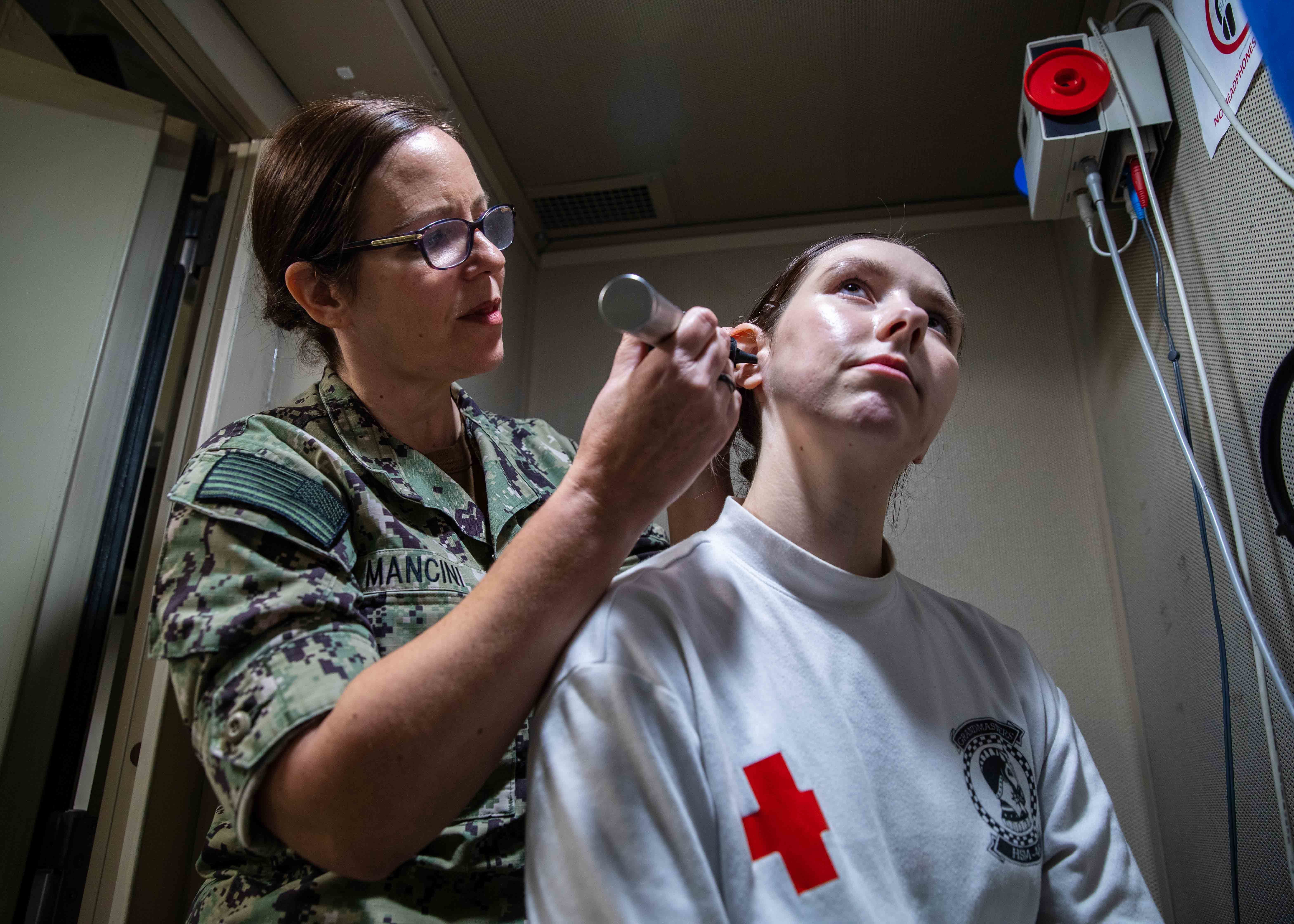 221115-N-IX644-1056 ADRIATIC SEA (Nov. 16, 2022) Lt. Cmdr. Mancini, assigned to Navy Medicine Readiness and Training Command Sigonella, performs an ear exam on Hospital Corpsman 3rd Class Maci Briscoe, assigned to Helicopter Maritime Strike Squadron (HSM) 46, aboard the Nimitz-class aircraft carrier USS George H. W. Bush (CVN 77), Nov. 16, 2022. NMRTC Sigonella Sailors embarked aboard George H.W. Bush to provide specialty training and medical examinations to the crew. Carrier Air Wing (CVW) 7 is the offensive air and strike component of Carrier Strike Group 10, George H.W. Bush Carrier Strike Group (GHWBCSG). The squadrons of CVW-7 are Strike Fighter Squadron (VFA) 86, VFA-103, VFA-136, VFA-143, Electronic Attack Squadron (VAQ) 140, Carrier Airborne Early Warning Squadron (VAW) 121, Helicopter Sea Combat Squadron (HSC) 5, and HSM-46. The GHWBCSG is on a scheduled deployment in the U.S. Naval Forces Europe area of operations, employed by U.S. Sixth Fleet to defend U.S., allied and partner interests. (U.S. Navy photo by Mass Communication Specialist Seaman Sasha Ambrose)